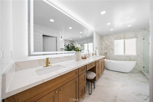 bathroom featuring double vanity, marble finish floor, recessed lighting, a soaking tub, and a sink