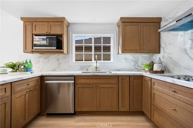 kitchen with a sink, wall chimney exhaust hood, backsplash, and black appliances