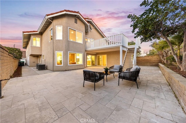 back of house at dusk featuring central air condition unit, a patio, and stairway