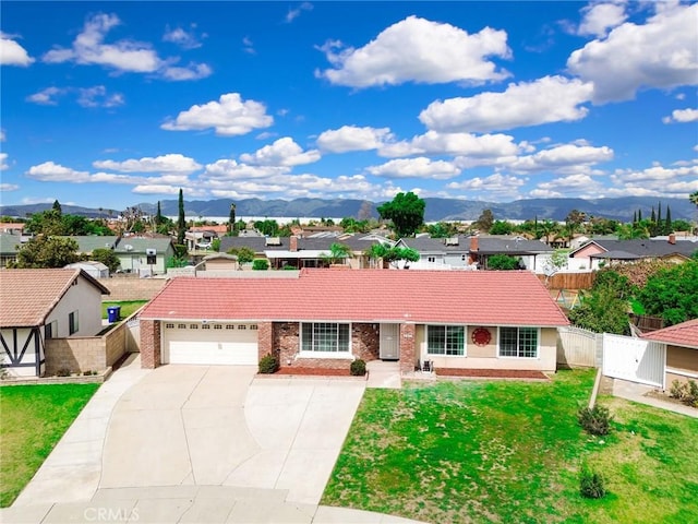 single story home featuring driveway, a tile roof, a mountain view, and a front yard