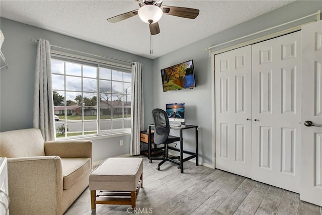 home office with baseboards, a textured ceiling, wood finished floors, and a ceiling fan