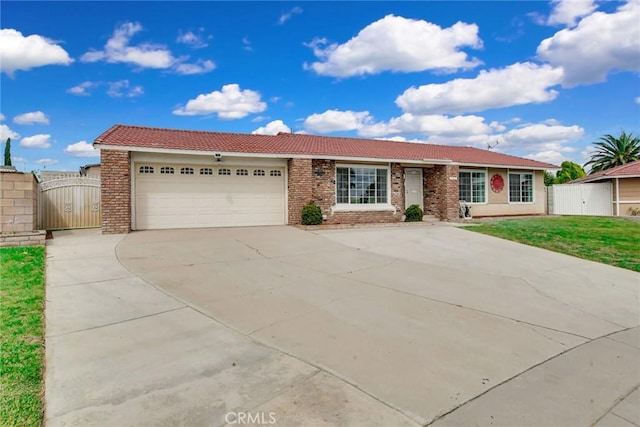 single story home featuring a tile roof, concrete driveway, a gate, a front lawn, and a garage