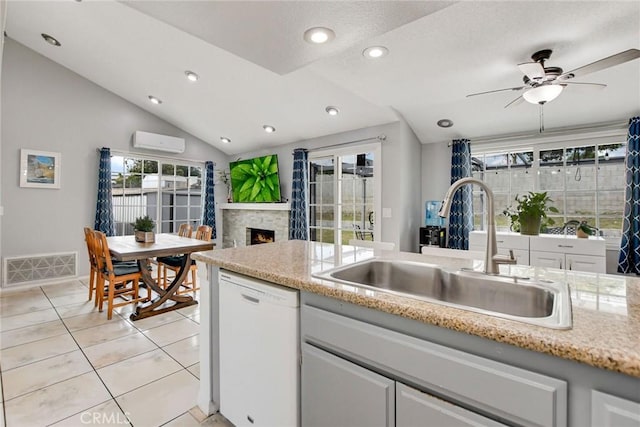 kitchen with light tile patterned flooring, a sink, white dishwasher, visible vents, and an AC wall unit