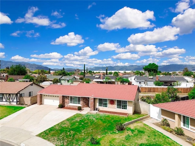 ranch-style home with a gate, a tiled roof, concrete driveway, a residential view, and a mountain view