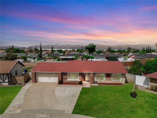 ranch-style house featuring concrete driveway, fence, a mountain view, and a yard