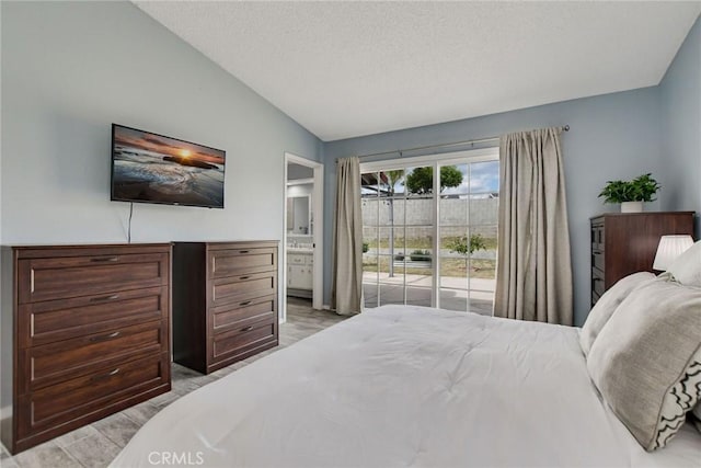 bedroom with a textured ceiling, lofted ceiling, ensuite bath, and access to outside