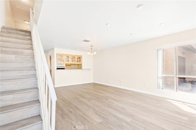 stairway featuring visible vents, baseboards, an inviting chandelier, and wood finished floors