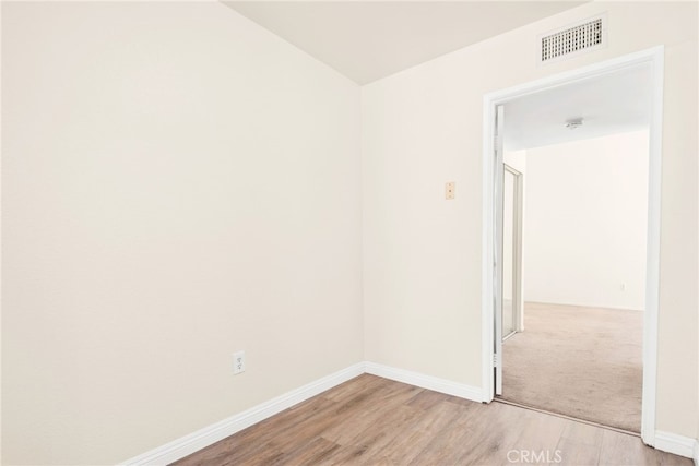 empty room with light wood-type flooring, baseboards, and visible vents