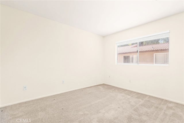 unfurnished room with baseboards and light colored carpet
