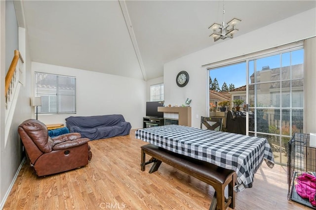 bedroom with access to exterior, wood finished floors, vaulted ceiling, and an inviting chandelier