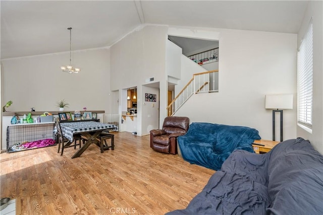 living room featuring a notable chandelier, high vaulted ceiling, stairs, and wood finished floors
