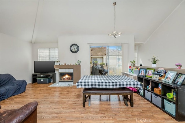 dining space featuring a chandelier, a fireplace, vaulted ceiling, and wood finished floors