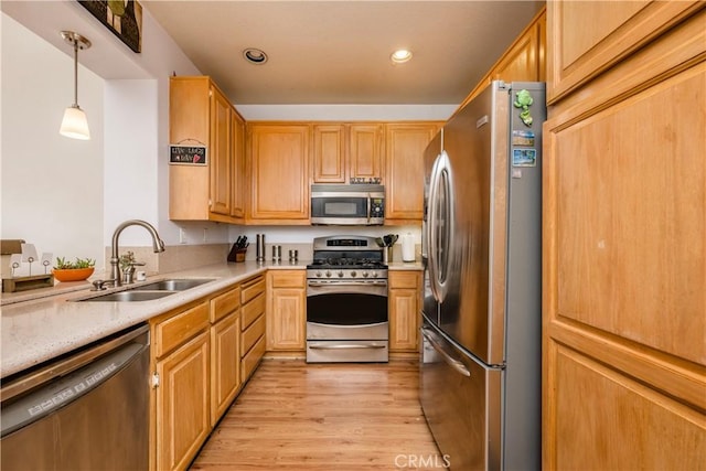 kitchen with light countertops, a sink, appliances with stainless steel finishes, and light wood-style flooring