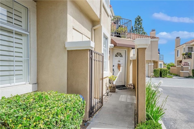 property entrance with a balcony and stucco siding