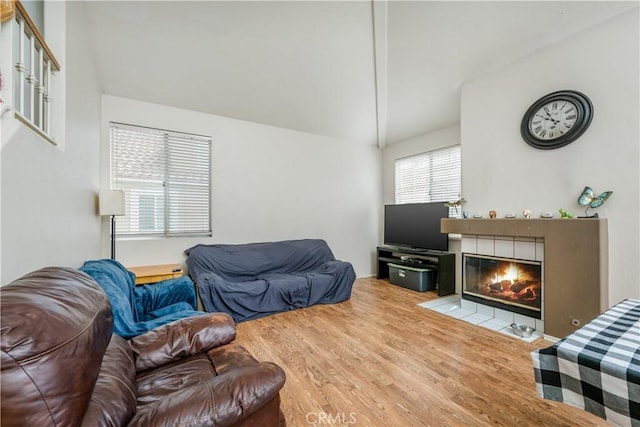 living area with a tile fireplace, lofted ceiling, and wood finished floors