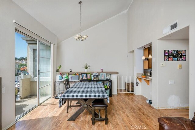 dining space featuring high vaulted ceiling, visible vents, light wood finished floors, baseboards, and an inviting chandelier