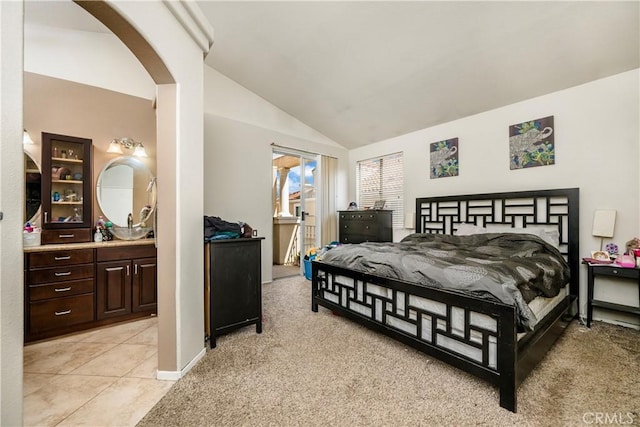 bedroom featuring baseboards, vaulted ceiling, arched walkways, and light tile patterned floors