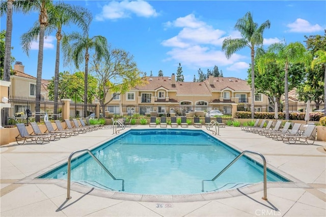 community pool featuring fence, a residential view, and a patio area
