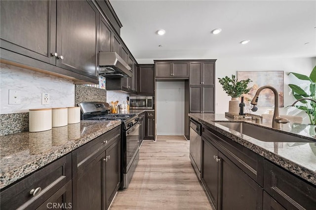 16022 Voyager Ave, Chino, CA 91708 - kitchen with stainless steel appliances, a sink, under cabinet range hood, dark stone countertops, and light wood-type flooring