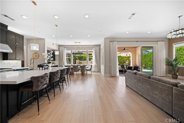 107 Balance, Irvine, CA 92618 - kitchen with open floor plan, light countertops, light wood finished floors, a breakfast bar, and pendant lighting
