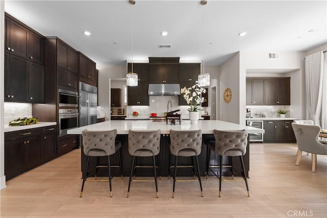 107 Balance, Irvine, CA 92618 - kitchen with built in fridge, under cabinet range hood, tasteful backsplash, wine cooler, and light countertops