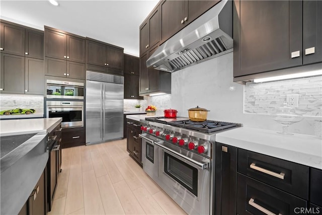 107 Balance, Irvine, CA 92618 - kitchen with high end appliances, ventilation hood, decorative backsplash, dark brown cabinetry, and light wood-style floors