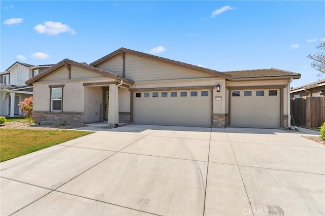view of front facade featuring stone siding, concrete driveway, stucco siding, fence, and a garage