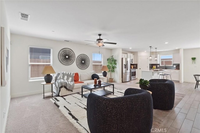 living area with light wood-style flooring, visible vents, baseboards, recessed lighting, and a ceiling fan