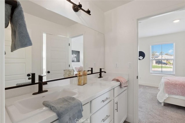 bathroom with ensuite bathroom, double vanity, baseboards, and a sink