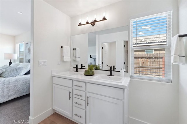 ensuite bathroom featuring double vanity, a sink, baseboards, and ensuite bathroom