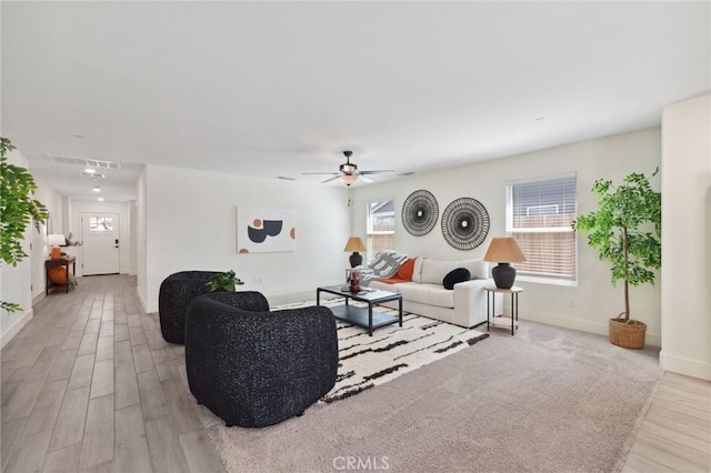 living room featuring baseboards, visible vents, wood finished floors, and ceiling fan