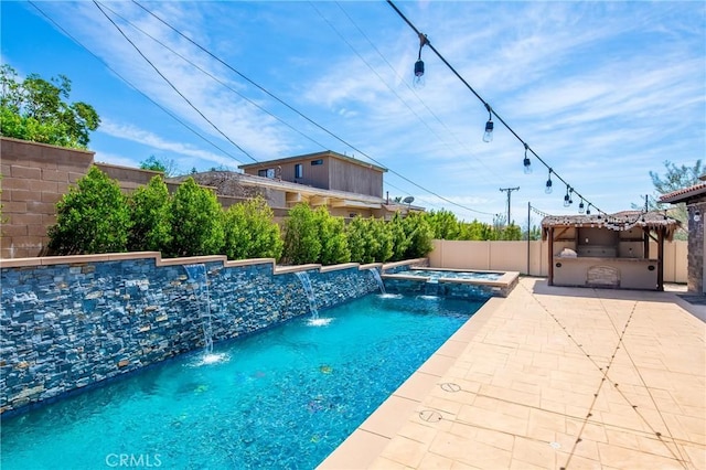 view of pool with a pool with connected hot tub, exterior kitchen, a patio, and a fenced backyard