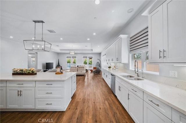 kitchen with white cabinetry, a sink, visible vents, light countertops, and open floor plan