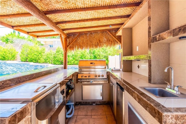 view of patio / terrace featuring area for grilling, a sink, a swimming pool, and exterior kitchen