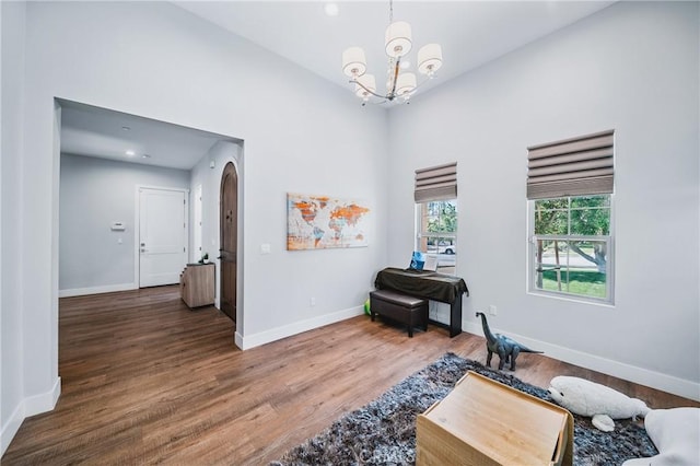 sitting room with arched walkways, an inviting chandelier, wood finished floors, and baseboards