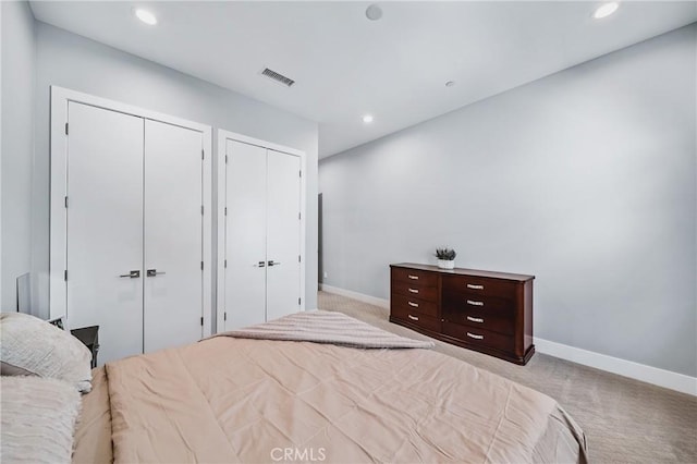 carpeted bedroom featuring baseboards, visible vents, two closets, and recessed lighting