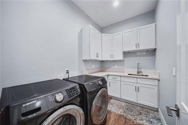 laundry area featuring wood finished floors, washer and dryer, cabinet space, a sink, and baseboards