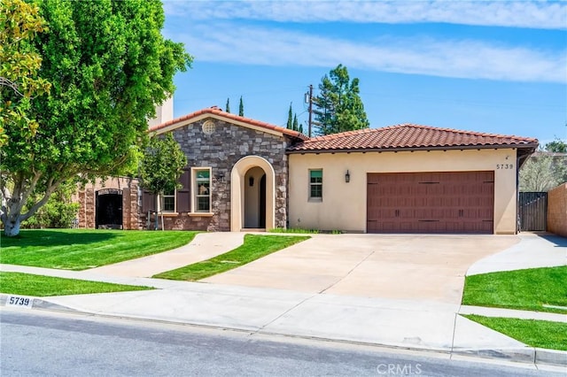 mediterranean / spanish home with a tile roof, a front yard, a garage, stone siding, and stucco siding