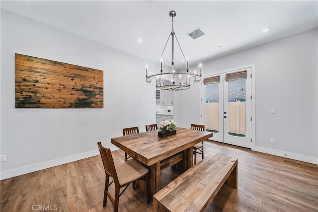 dining area with wood finished floors, visible vents, a notable chandelier, and baseboards