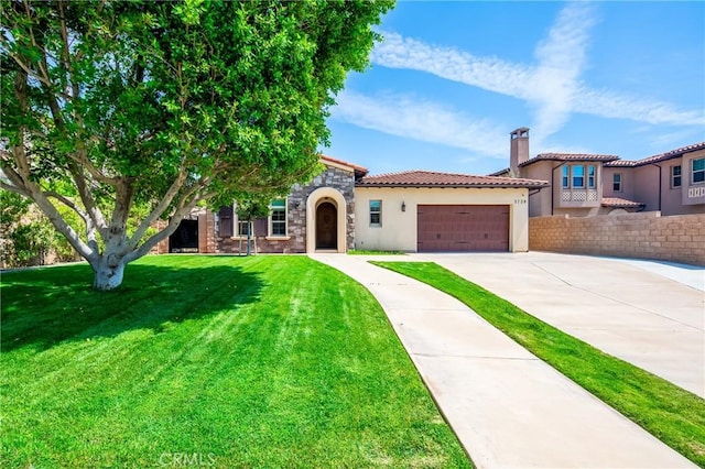 mediterranean / spanish house with stucco siding, fence, a front lawn, concrete driveway, and an attached garage
