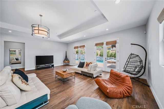 living room with recessed lighting, a raised ceiling, wood finished floors, and baseboards