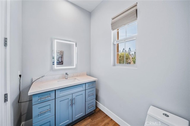 bathroom featuring toilet, vanity, wood finished floors, and baseboards