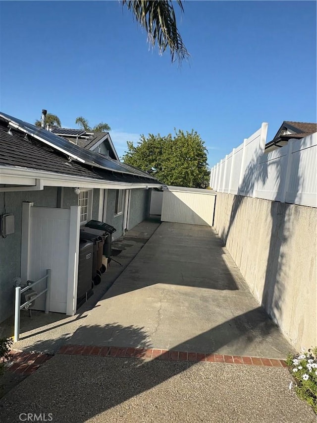 view of property exterior featuring roof mounted solar panels, a patio area, fence, and stucco siding