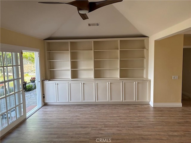 spare room featuring wood finished floors, ceiling fan, baseboards, lofted ceiling, and visible vents