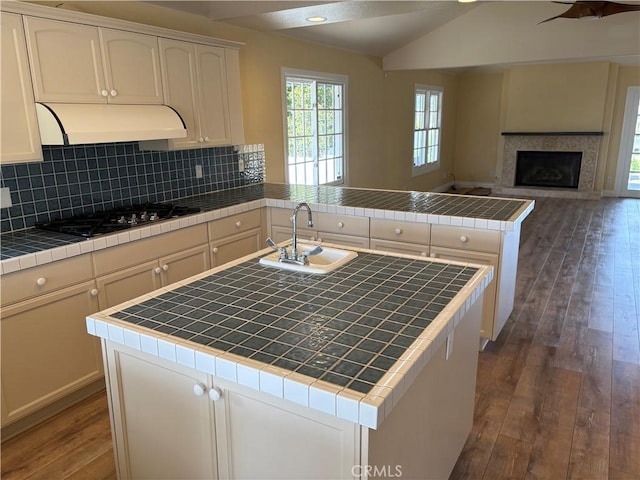 kitchen with tile counters, gas stovetop, a sink, and range hood