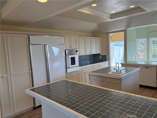 kitchen with wood finished floors, tile counters, white appliances, and a raised ceiling