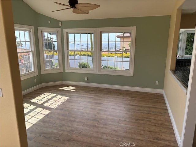 unfurnished room featuring a ceiling fan, vaulted ceiling, a healthy amount of sunlight, and wood finished floors