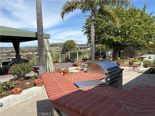 view of patio with grilling area, fence, an outdoor kitchen, and a gazebo