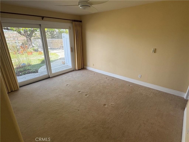 carpeted empty room with a ceiling fan and baseboards