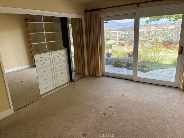 unfurnished bedroom featuring baseboards, carpet flooring, and access to outside